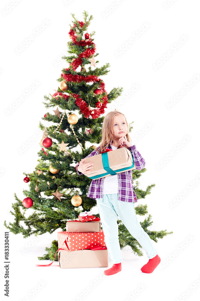 Portrait of little girl standing near Christmas tree with gift box in her hands on white background Portrait of little girl standing near Christmas tree with gift box in her hands on white background