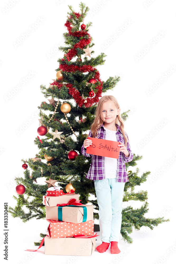 Portrait of little girl standing near Christmas tree with letter to Santa in her hands on white background Portrait of little girl standing near Christmas tree with letter to Santa in her hands on white background