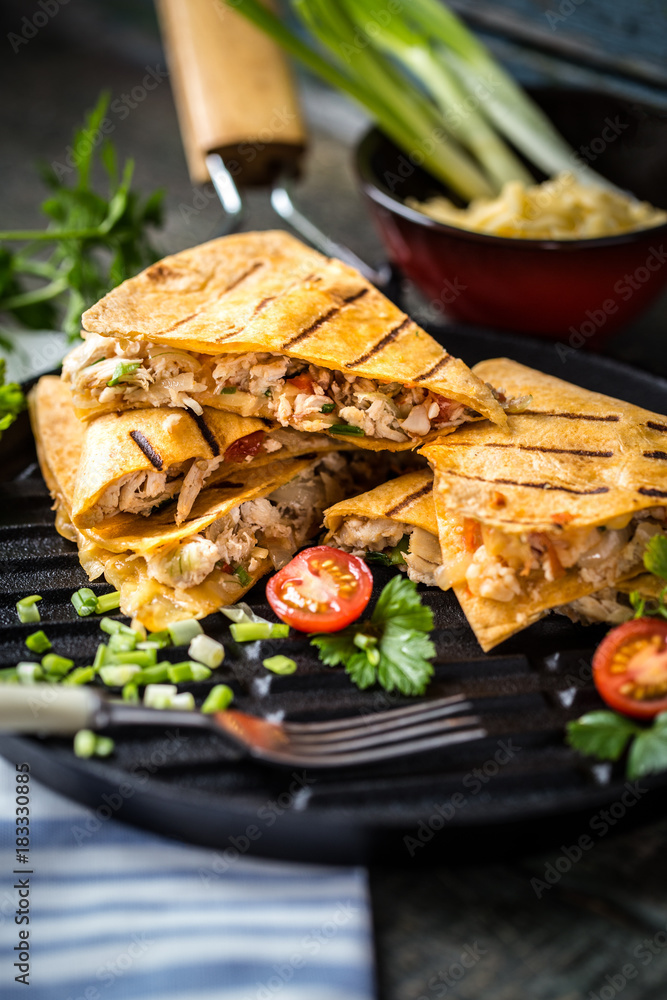 Mexican food quesadilla with grilled chicken, salsa and cheese, with greens and vegetables Mexican food quesadilla with grilled chicken, salsa and cheese, with greens and vegetables
