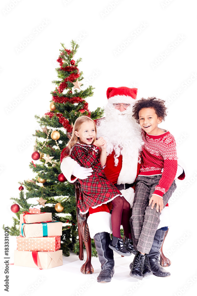Santa Claus sitting in chair near Christmas tree with multi-ethnic boy and girl on his lap Santa Claus sitting in chair near Christmas tree with multi-ethnic boy and girl on his lap