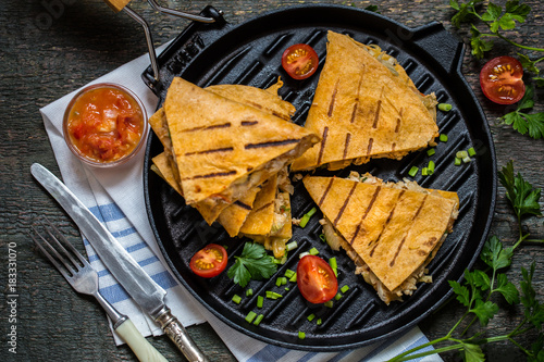 Mexican food quesadilla with grilled chicken, salsa and cheese, with greens and vegetables