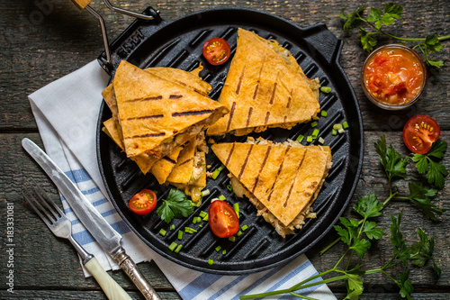 Mexican food quesadilla with grilled chicken, salsa and cheese, with greens and vegetables