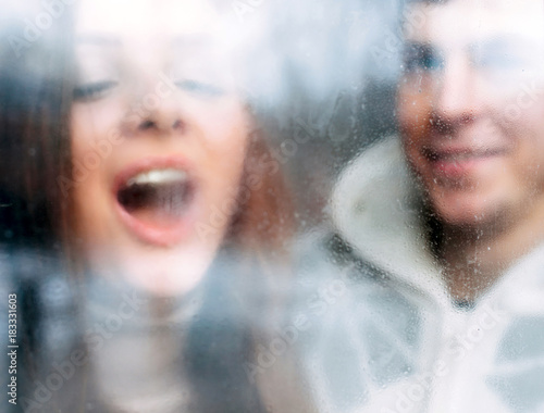 Young couple in love closeup winter cold portrait looking thru the window