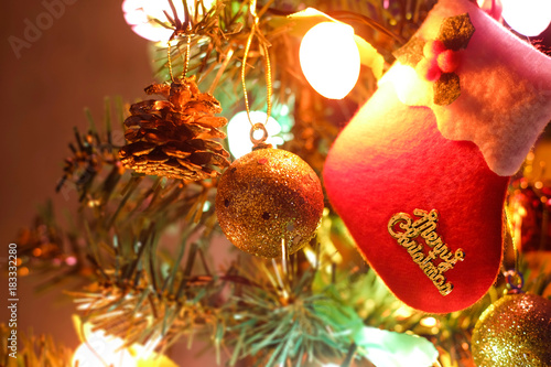 red Christmas stocking hunging on Christmas tree with shinning color lights and  decorations photo