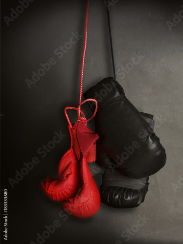pair of new children red gloves for karate and old adult gloves for boxing hang on a dark gray background