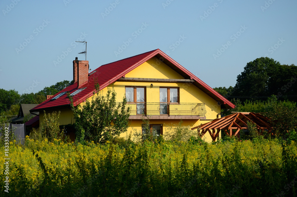 A new rural home with a blue sky and green bushes