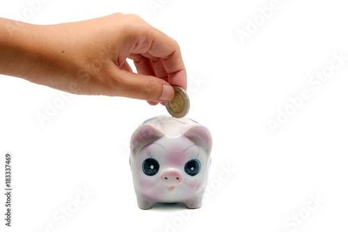 Hand saving a coin into pig...