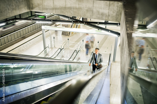 Businessman on an escalator on a metro station.