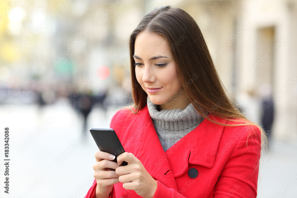 Serious woman using a smart phone in winter