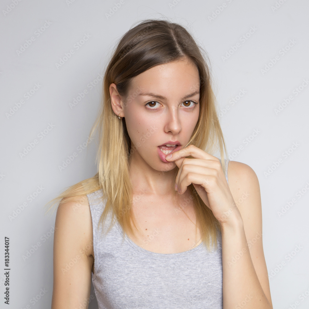 Beautiful brunette caucasian woman in grey blouse with bright emotions standing on a neutral grey background. Her hands make a gesture. She act sexy, seductive Beautiful brunette caucasian woman in grey blouse with bright emotions standing on a neutral grey background. Her hands make a gesture. She act sexy, seductive
