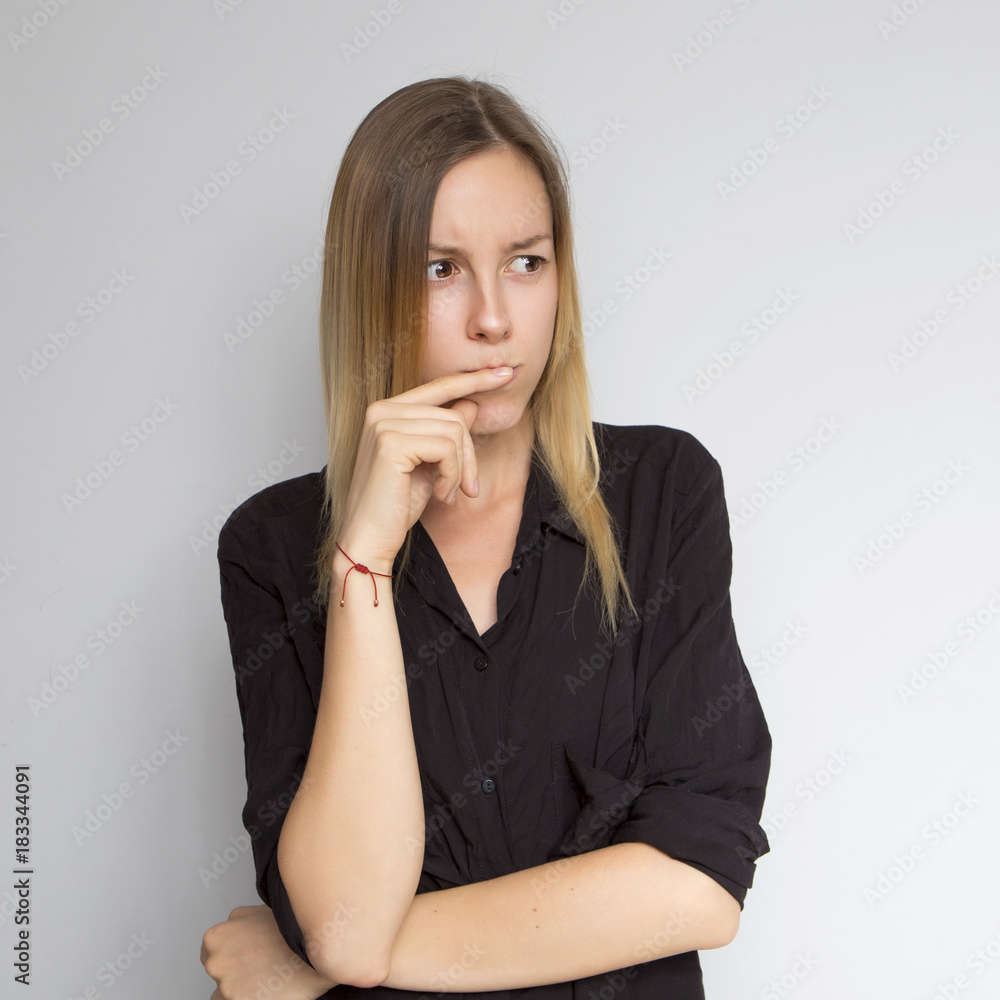Beautiful brunette caucasian woman in dark black blouse with bright emotions standing on a neutral grey background. Her hands make a gesture. She thoughtful Beautiful brunette caucasian woman in dark black blouse with bright emotions standing on a neutral grey background. Her hands make a gesture. She thoughtful