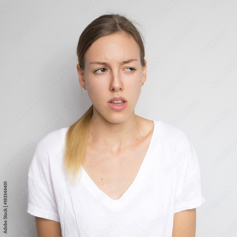 Beautiful brunette caucasian woman in white blouse with bright emotions standing on a neutral grey background. Her hands make a gesture. She thoughtful Beautiful brunette caucasian woman in white blouse with bright emotions standing on a neutral grey background. Her hands make a gesture. She thoughtful