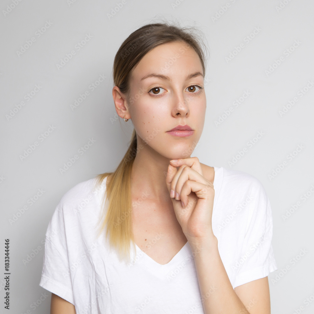 Beautiful brunette caucasian woman in white blouse with bright emotions standing on a neutral grey background. Her hands make a gesture. She thoughtful Beautiful brunette caucasian woman in white blouse with bright emotions standing on a neutral grey background. Her hands make a gesture. She thoughtful