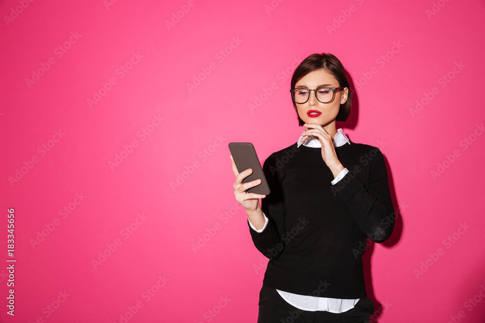 Portrait of a pensive attractive businesswoman looking at mobile phone Portrait of a pensive attractive businesswoman looking at mobile phone