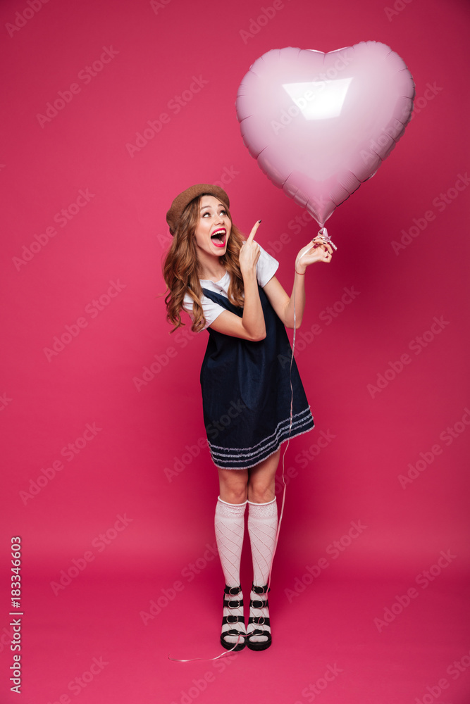 Pretty amazed lady pointing at air balloon like heart isolated Pretty amazed lady pointing at air balloon like heart isolated