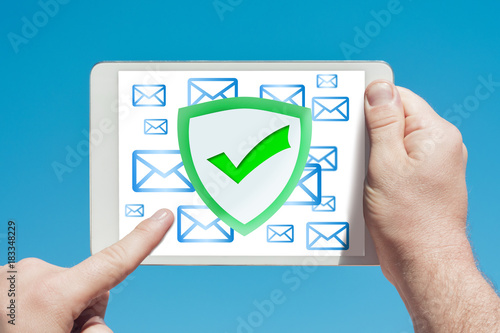 Man holding a tablet device pointing at an anti-spam, security firewall icon