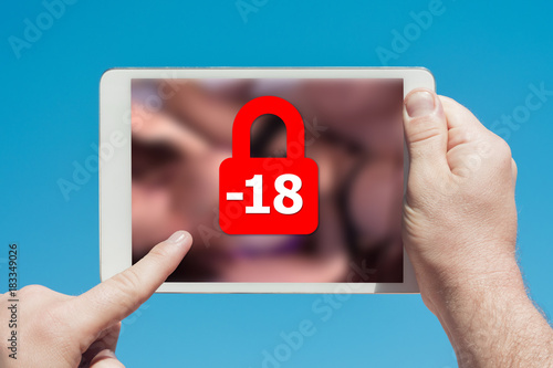 Man holding a tablet device showing lock icon denying permission to people under 18 to watch adult content photo