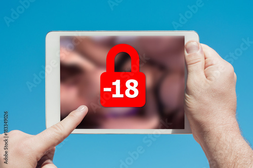 Man holding a tablet device showing lock icon denying permission to people under 18 to watch adult content