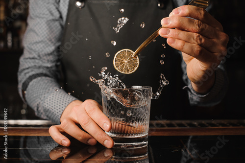 Bartender decorating a glass with splashing drink