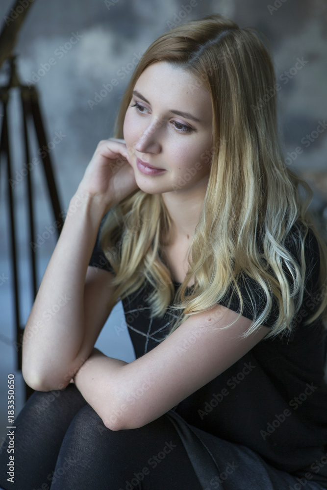 Cute blonde caucasian woman sitting in loft grunge trendy minimalistic interior, smiling cheerfully Cute blonde caucasian woman sitting in loft grunge trendy minimalistic interior, smiling cheerfully