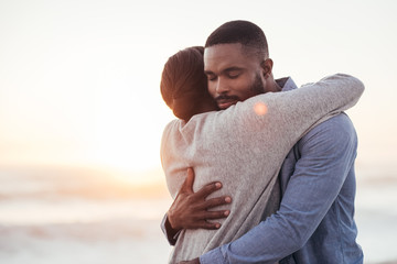 Content young African couple embracing each other at the beach