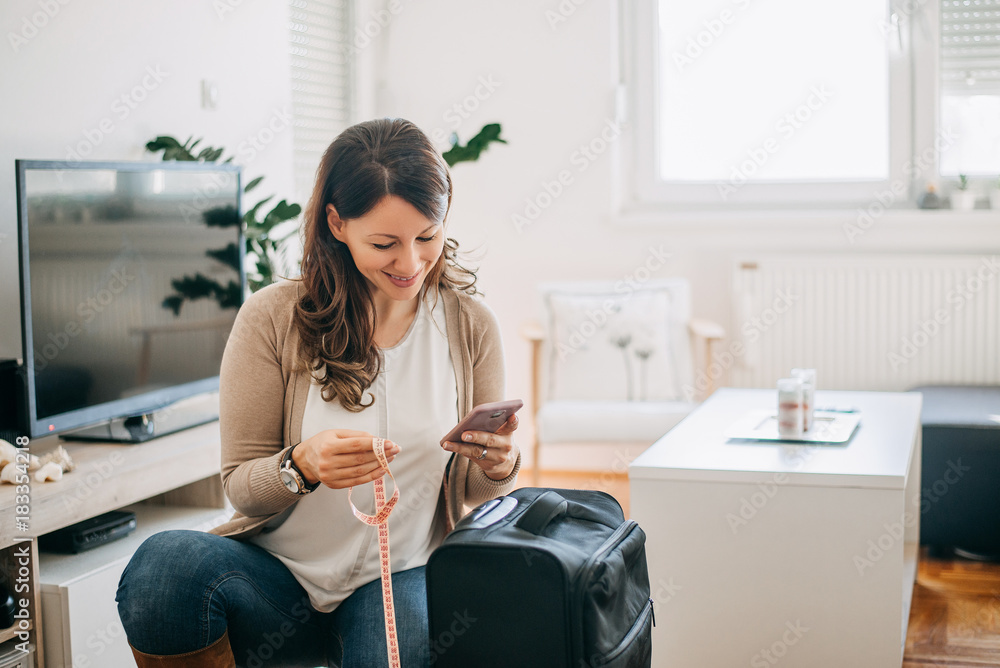 Woman checking on phone airport baggage size requirements. Woman checking on phone airport baggage size requirements.