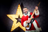 Happy Santa with a guitar is dancing against the background of a big electric star in Christmas.