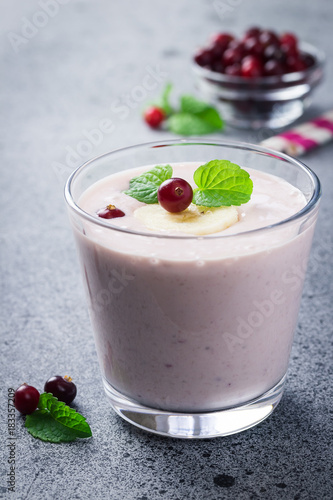 Orange cranberry blueberry banana smoothie on concrete or stone background. Selective focus, copy space, close up. 