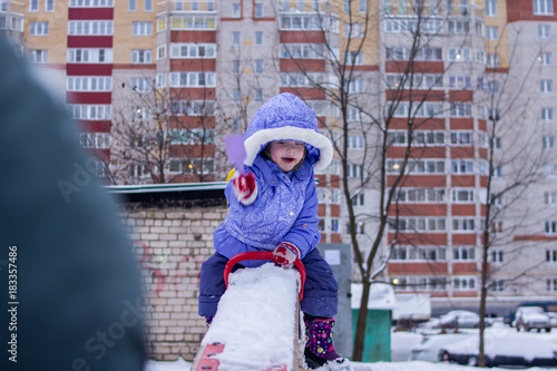 little girl swinging on a swing in a playground on a winter day