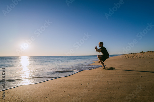 Man doing Yoga at sunset on a beach in Portugal