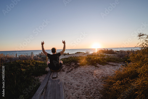 Man watching the sunset in Portugal with hands up