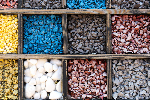 Many different color stones in wooden boxes as background