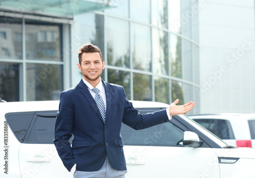 Salesman standing near new car outdoors