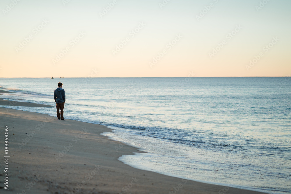 Man watching the sunrise and walking around on the beach in Portugal