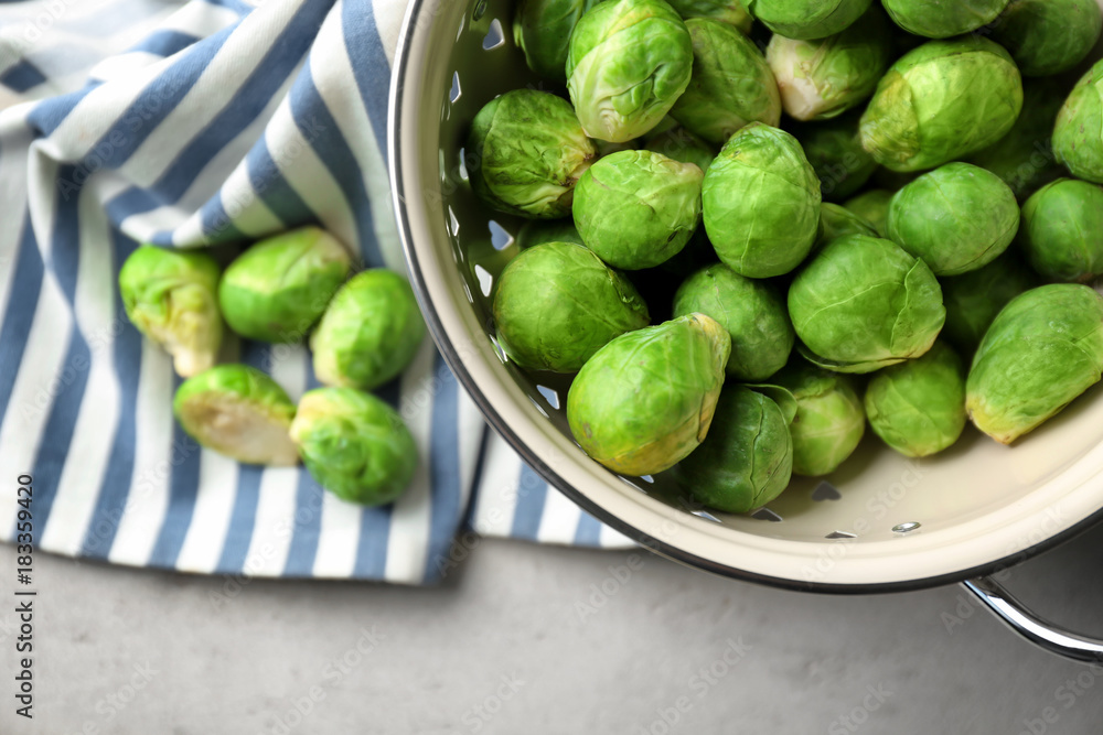 Colander with fresh raw Brussels sprouts on table Colander with fresh raw Brussels sprouts on table