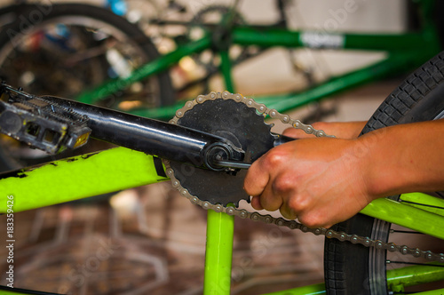 Bicycle mechanic adjusting the bicycle pedal in a workshop in the repair process, in a blurred background