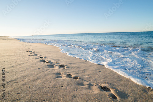 Footsteps in sand on a beach in portugal at sunrise