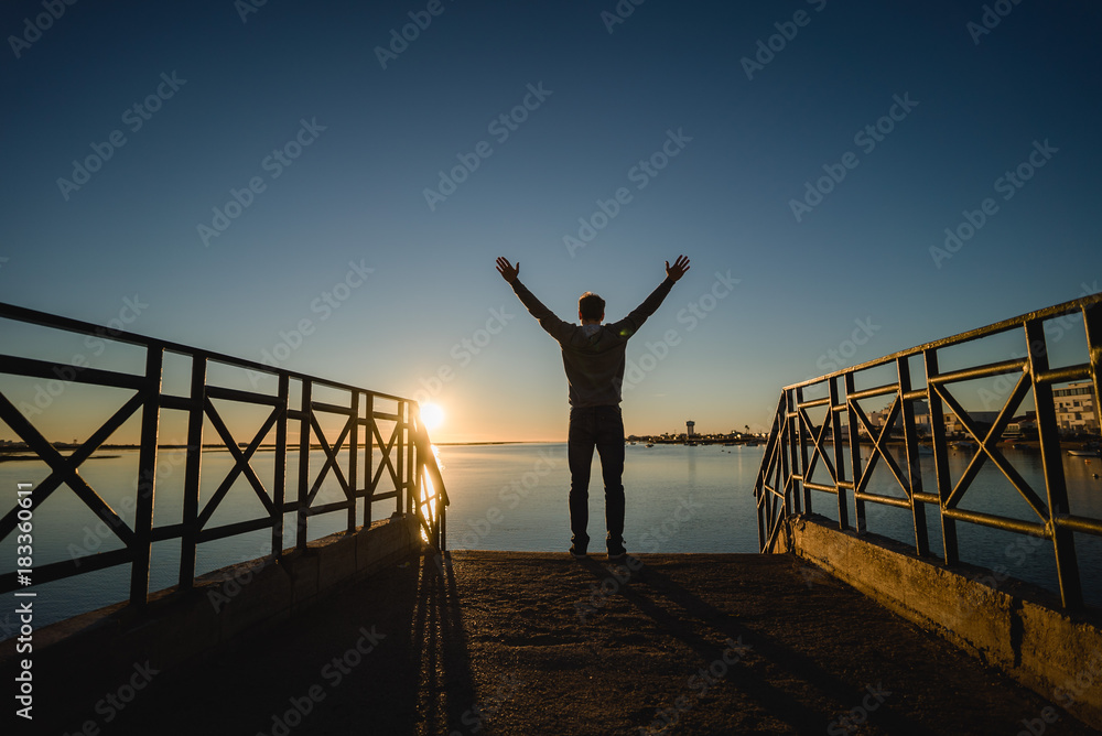 Man watching the sunrise from a bridge in Portugal
