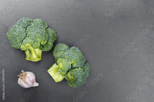 inflorescence of raw broccoli and garlic on a slate board
