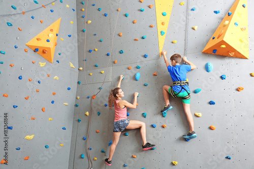 Young boy and instructor climbing wall in gym