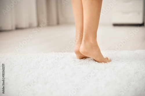 Woman standing on soft white carpet at home © Africa Studio