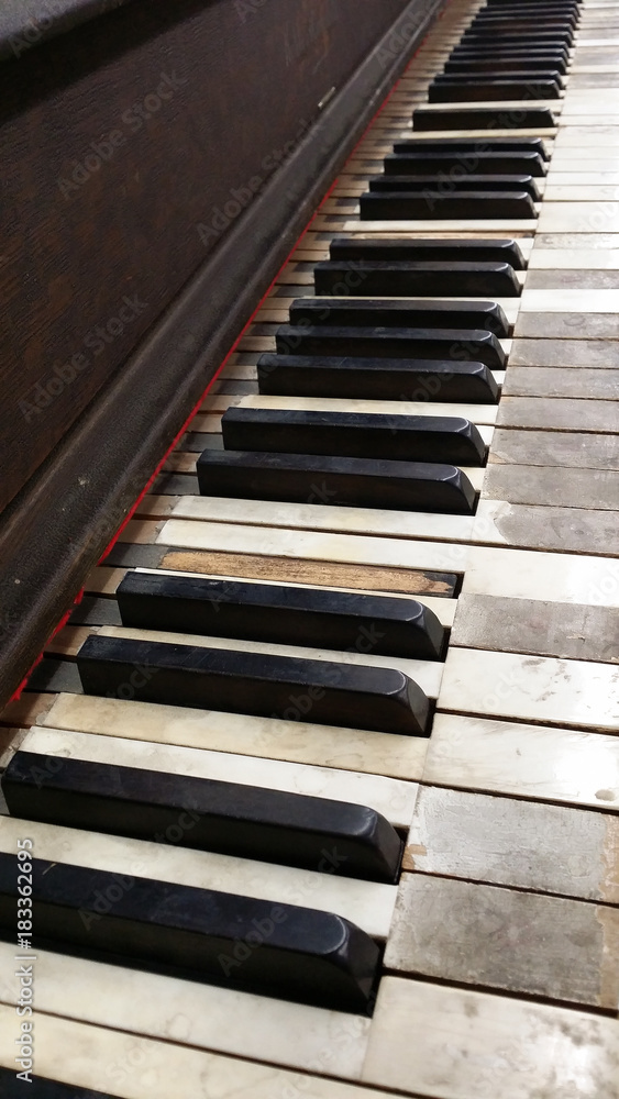 Side view of old distressed wooden Kohler and Campbell piano that has been abandoned. The white keys are stained and damaged. The black keys are dinged and some are missing. Side view of old distressed wooden Kohler and Campbell piano that has been abandoned. The white keys are stained and damaged. The black keys are dinged and some are missing.