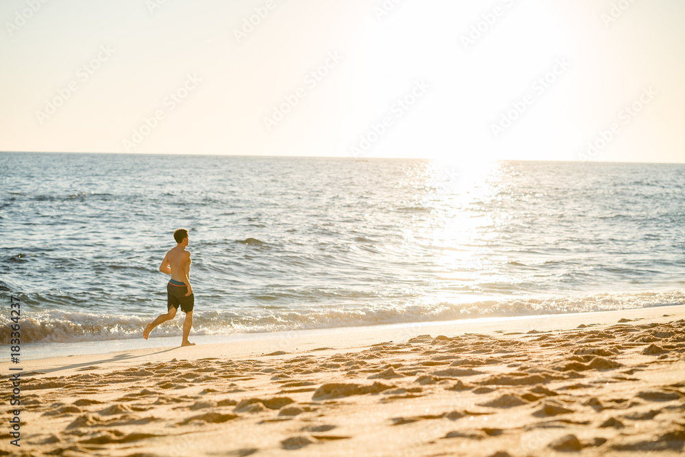 Man running on the beach at sunset