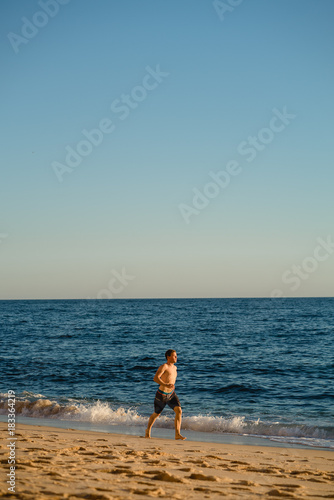 Man running on the beach at sunset