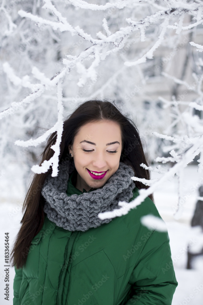 Young woman stays in the frosty forest.