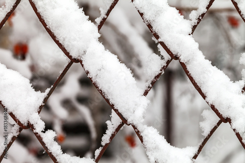 The grid of metal slabs is covered with snow. photo