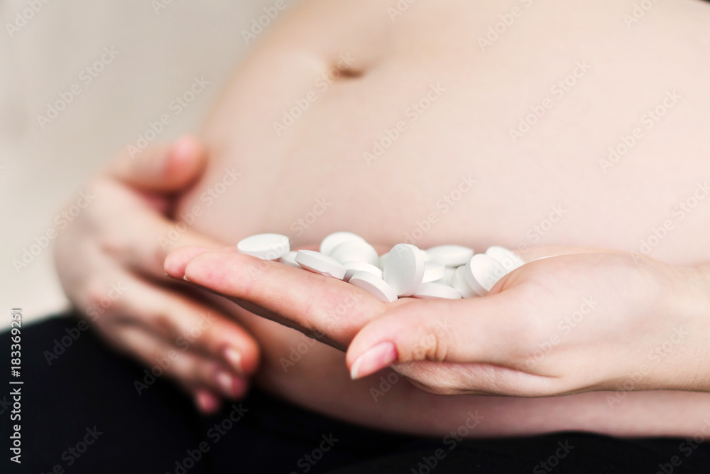 pregnant woman holding white pills or vitamins in hand pregnant woman holding white pills or vitamins in hand
