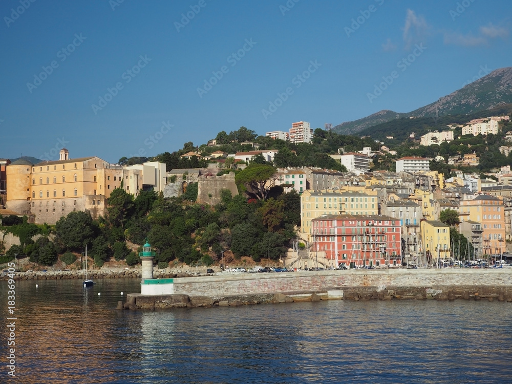 Corsica Bastia port view from sea on harbour with  green and old town houses yeachts and blue sky background
