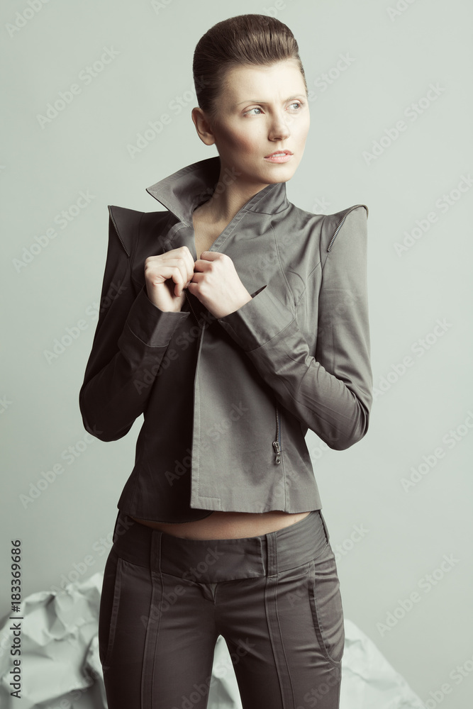 Art fashion, haute couture concept. Portrait of androgynous model with short hair holding lapels, posing over gray background. Pale skin, natural make-up. Futurism style. Close up. Studio shot Art fashion, haute couture concept. Portrait of androgynous model with short hair holding lapels, posing over gray background. Pale skin, natural make-up. Futurism style. Close up. Studio shot