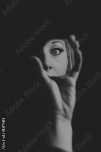 Woman looking at her eye in small mirror artistic conversion